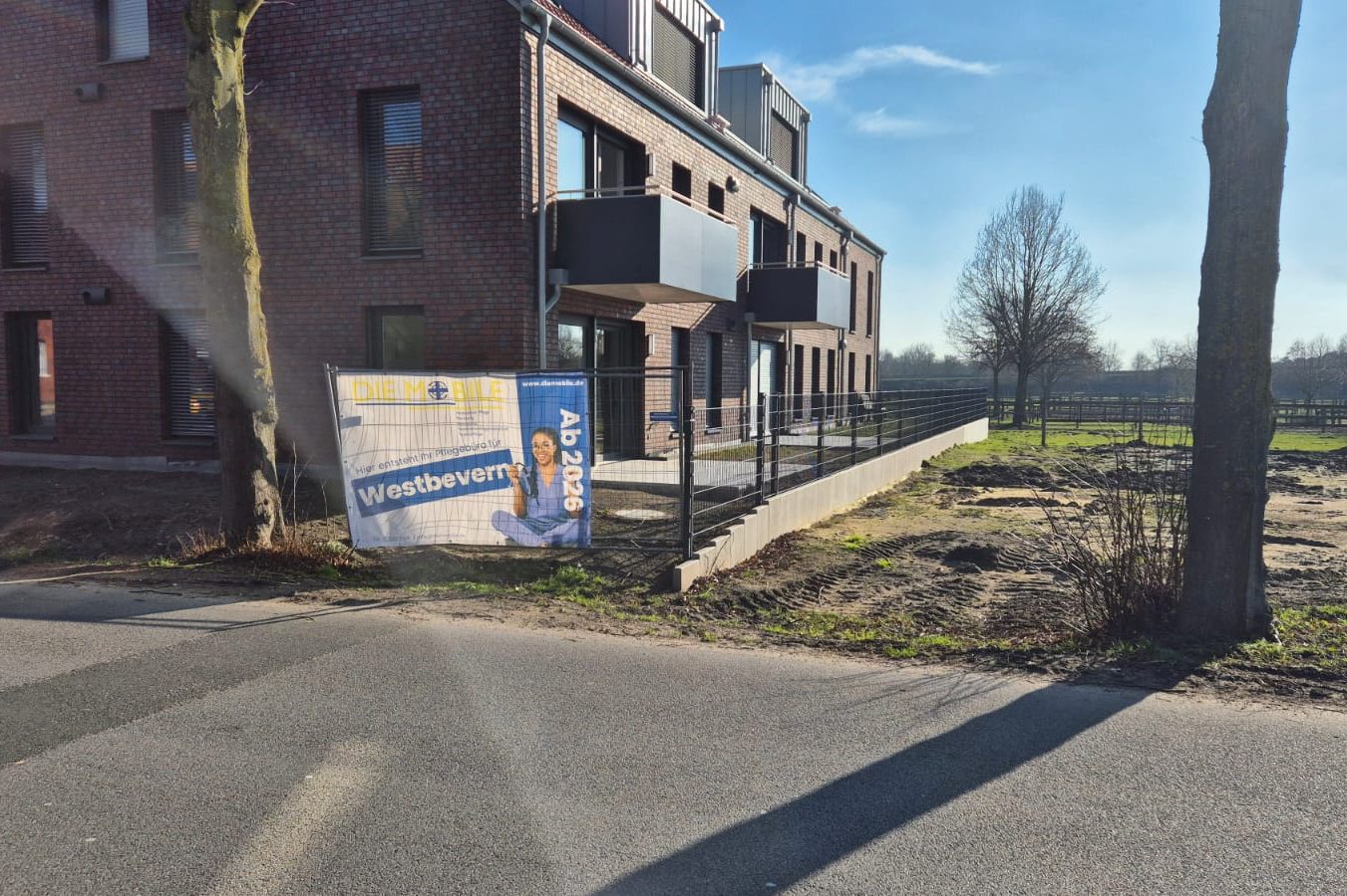 Gebäude in Telgte mit einem großen Schild und buntem Herbstbaum im Vordergrund.